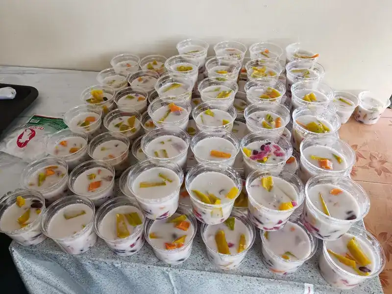 Rows of cups in a creamy white base, topped with yellow, orange and red pieces
