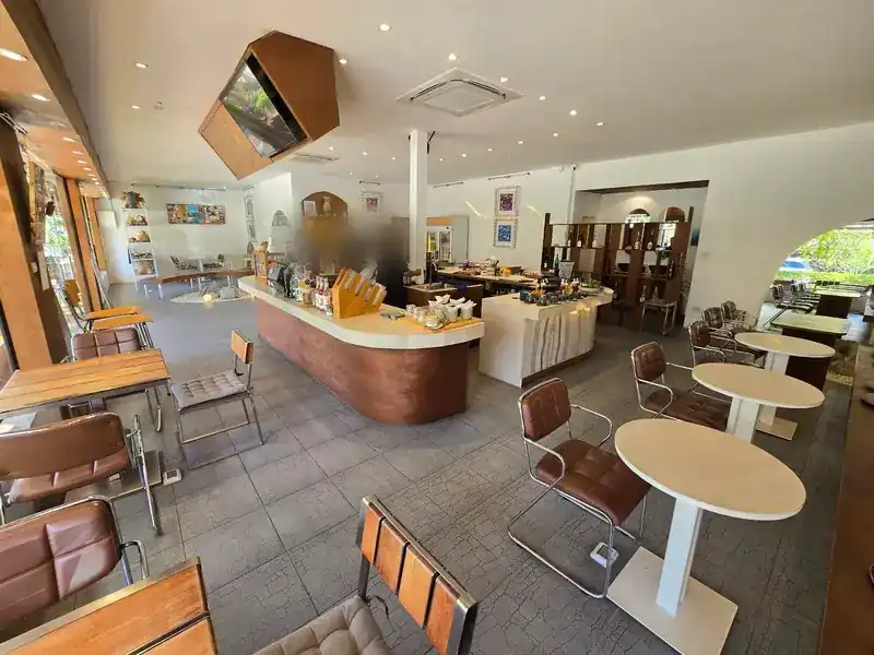 The main room: a curved walnut counter, white walls with arched openings, leather chairs and round stone tables