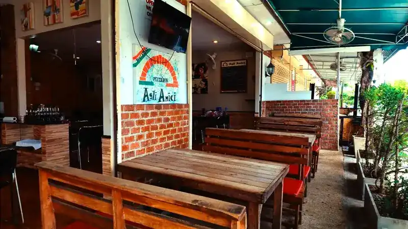 Wooden tables and benches by a brick wall on the covered terrace