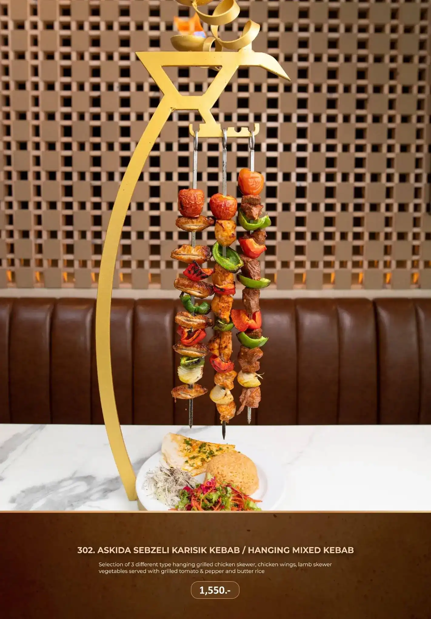 Three skewers of grilled chicken, lamb, tomato and green pepper hanging from a brass stand over a plate of rice and salad