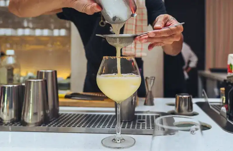 A cocktail being strained into a glass at the bar