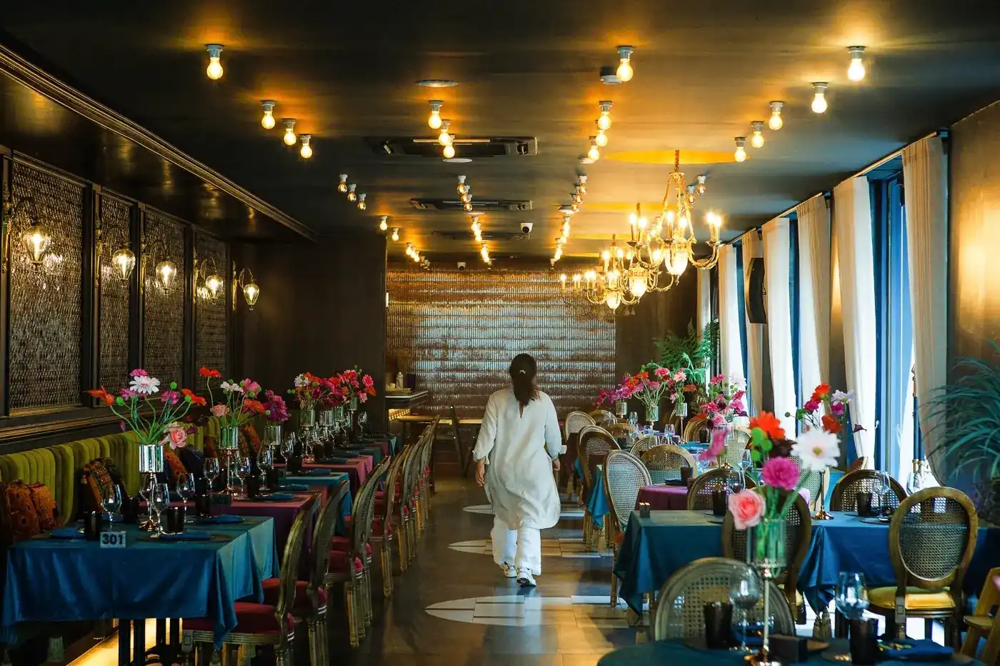 The dining room: deep-blue tablecloths, cane-backed chairs, flowers on every table and chandeliers overhead