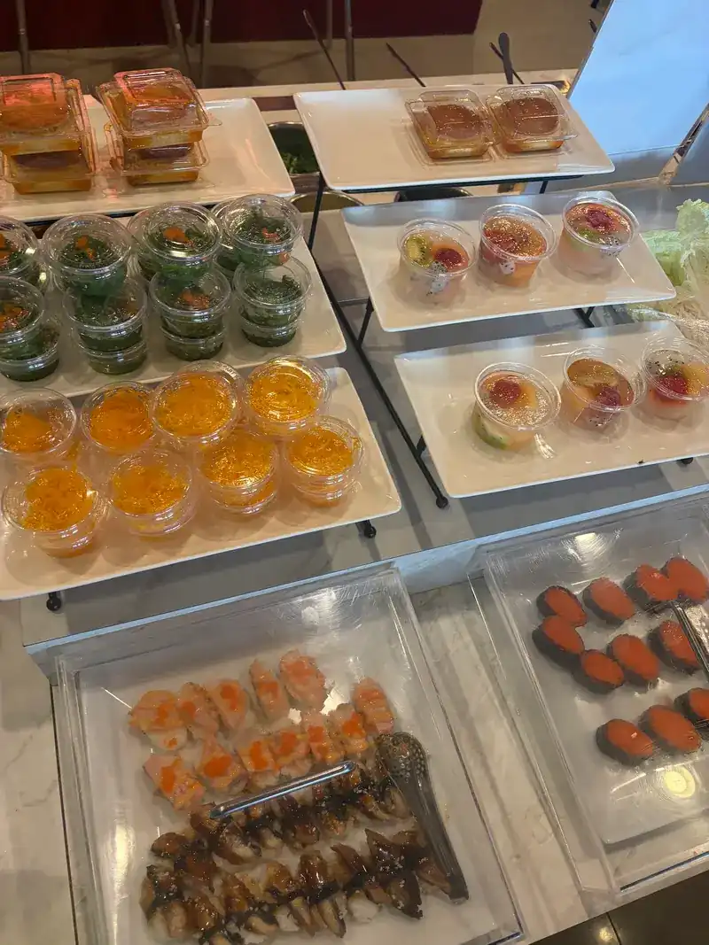 Sushi and small dessert cups laid out on white trays