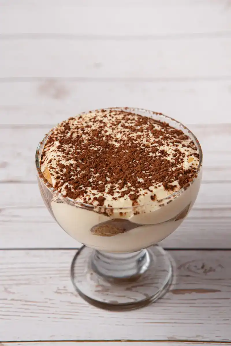 Tiramisu in a glass bowl dusted with cocoa