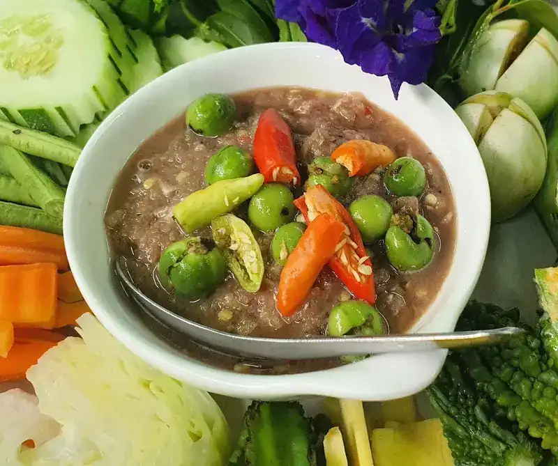 A chilli dip with pea aubergines, fresh vegetables and butterfly pea flowers