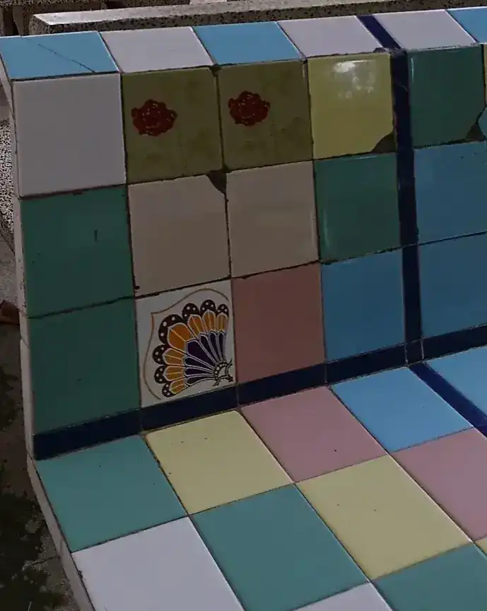 The tiled bench: teal, yellow, pink and blue tiles, two with red roses and one with a peacock
