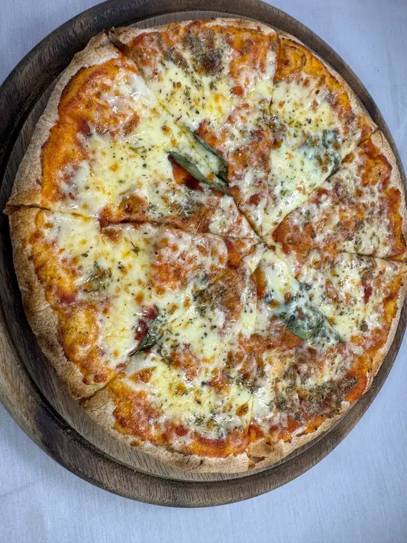 A cheese pizza with herbs on a wooden board
