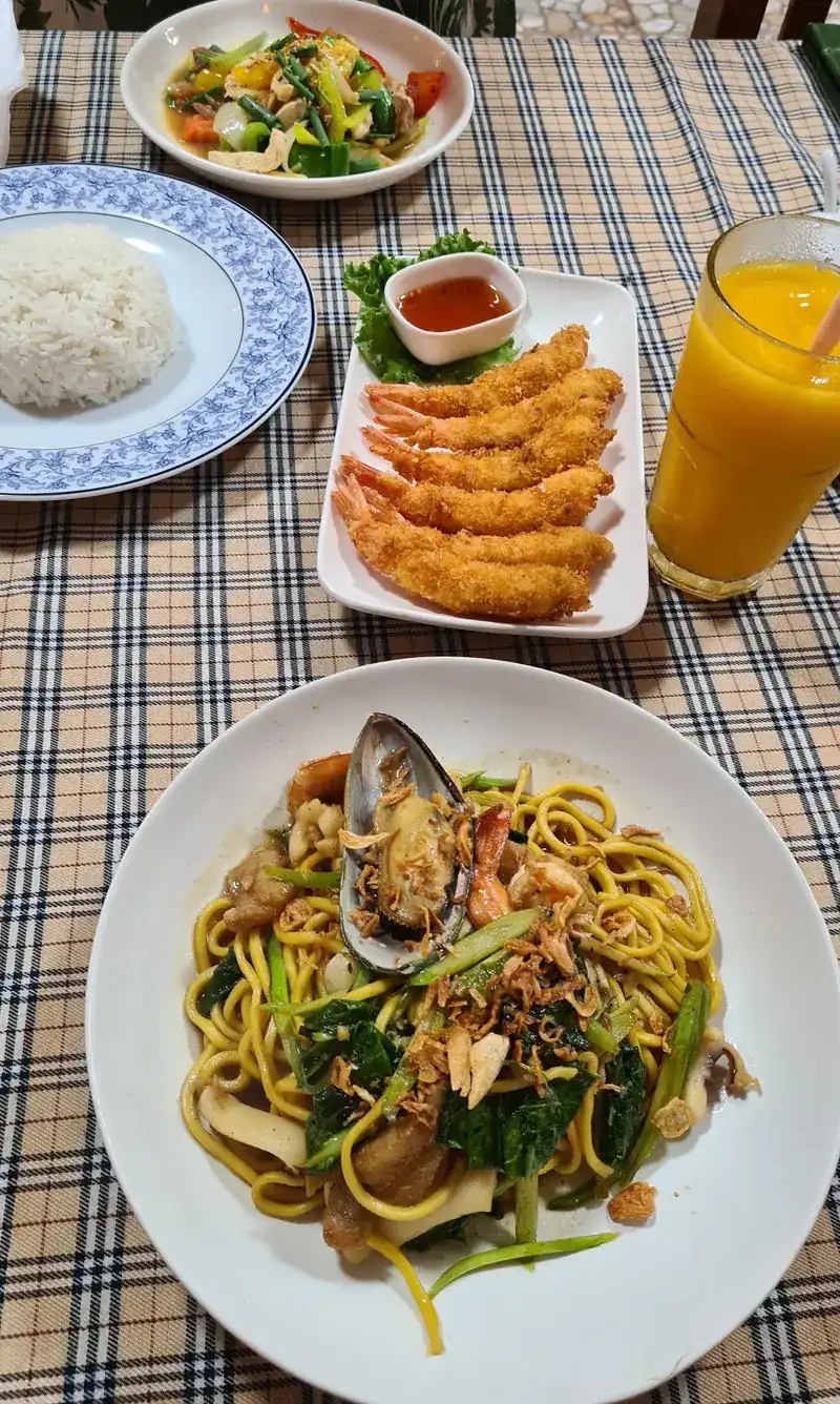 A table with seafood spaghetti, fried shrimp, stir-fried vegetables and rice