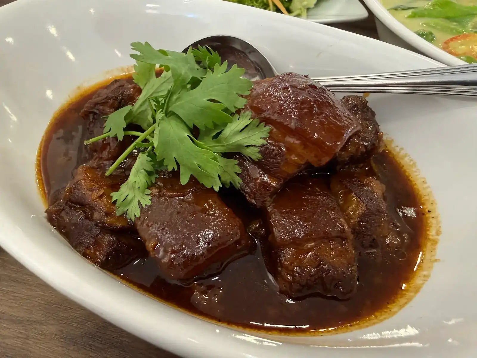 Moo hong: pieces of braised pork in a dark, glossy sauce, topped with coriander