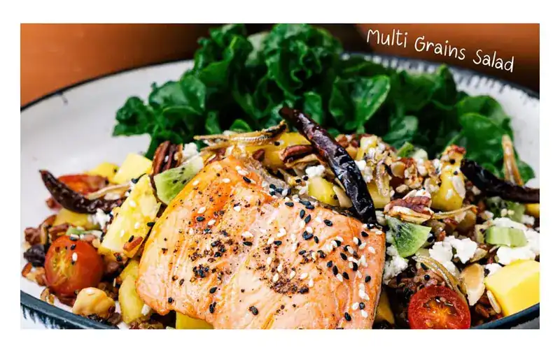 Grilled salmon with sesame on a salad of grains, mango, kiwi, tomato and greens