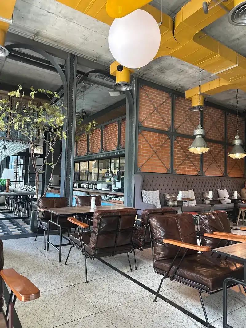 Leather armchairs by a brick wall under yellow ducts