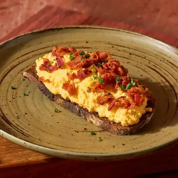 Scrambled egg and crisp bacon on a slice of sourdough toast
