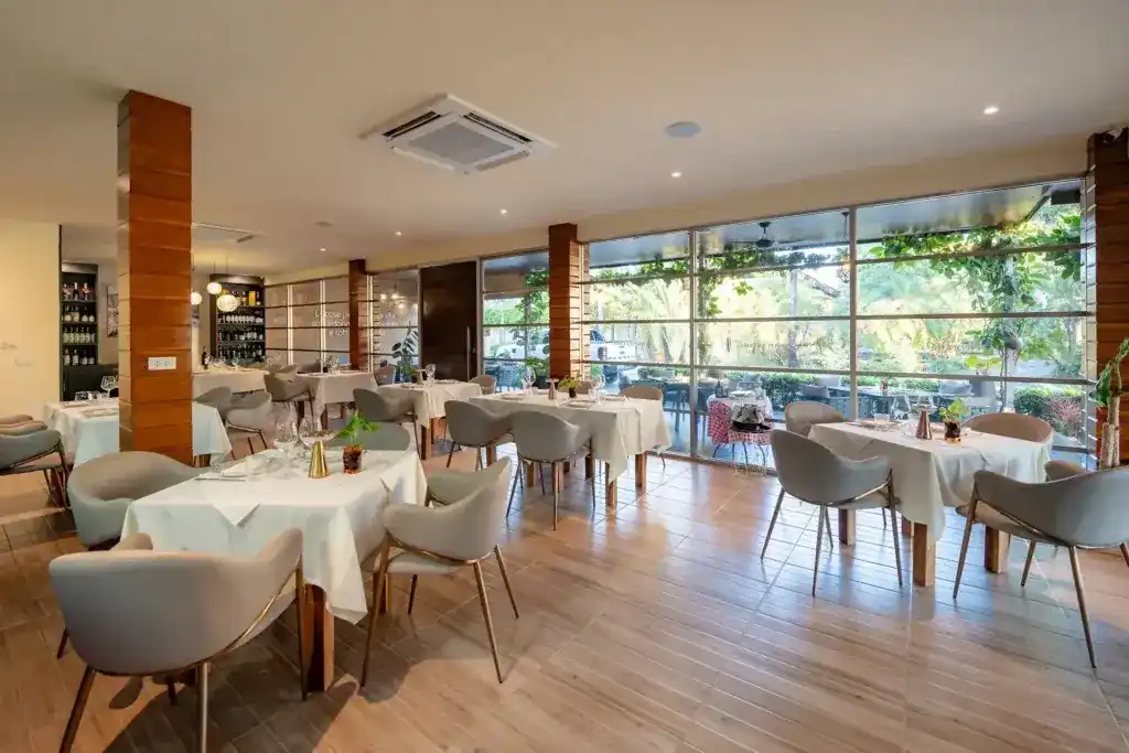 The dining room at La Napoletana, white tablecloths and a glass wall onto the garden