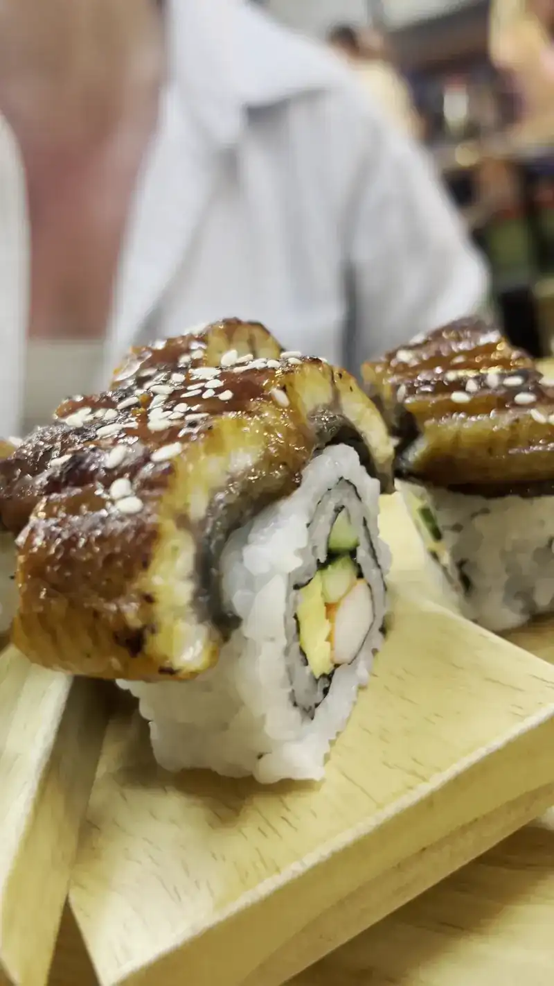Close-up of an unagi roll topped with glazed eel and sesame