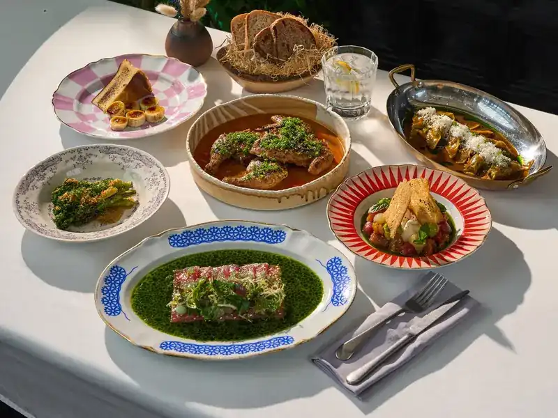 A table at ETNA laid with shared dishes, bread and patterned plates in the afternoon sun