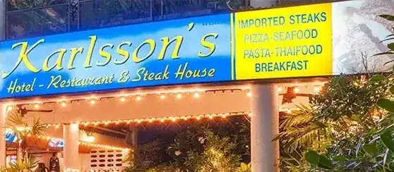 The blue and yellow Karlsson's sign above the restaurant entrance, lit in the evening