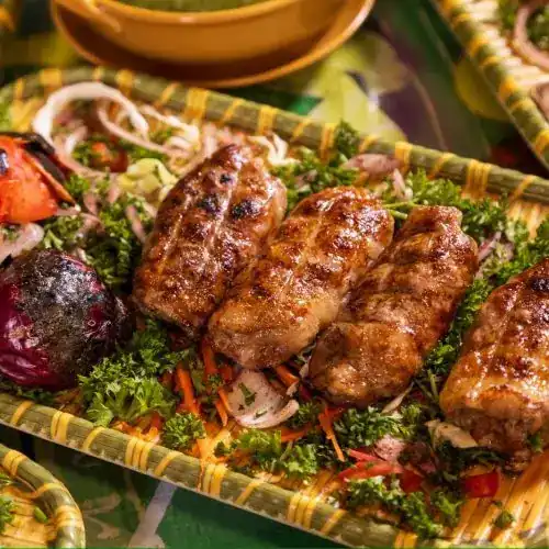 Grilled kofta on parsley, onion and carrot in a woven tray