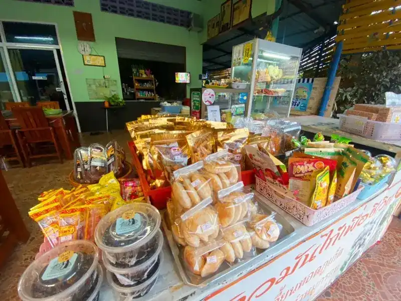 The front of the shop: green walls, wooden tables inside, and a counter of packed snacks under the shop's sign
