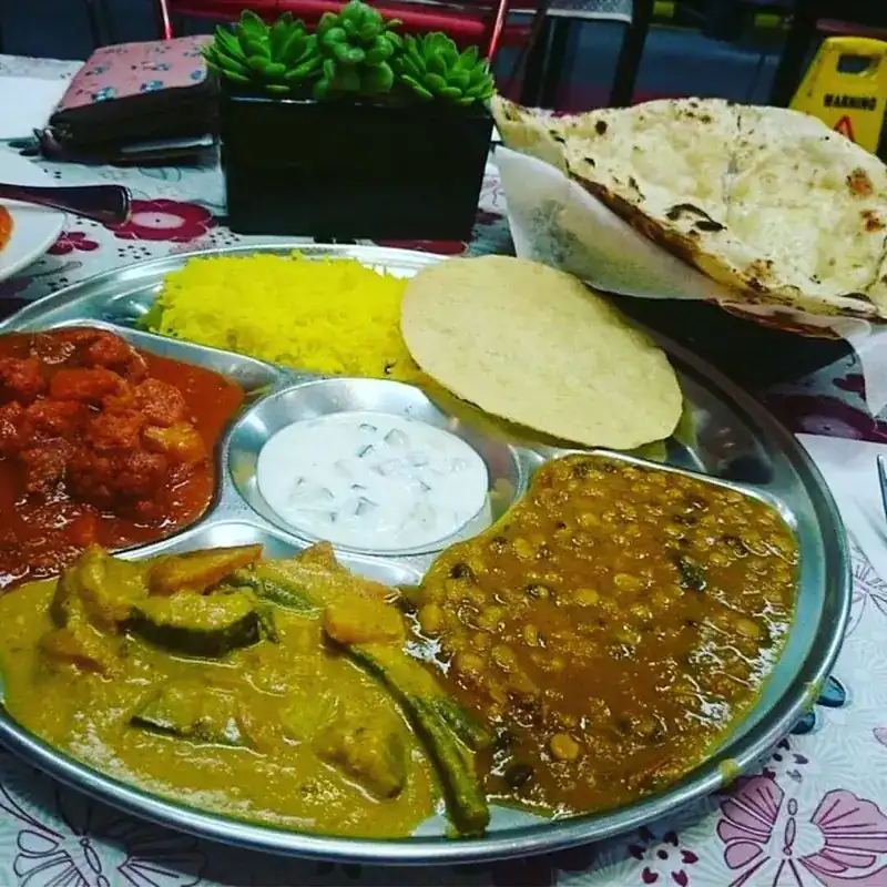 A thali with rice, dal, curries, raita, papad and naan