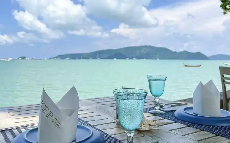 A table set with blue plates and turquoise glasses, looking across the bay to the hills