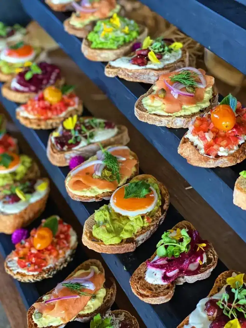 Rows of bruschettas topped with smoked salmon, avocado, tomato and beetroot