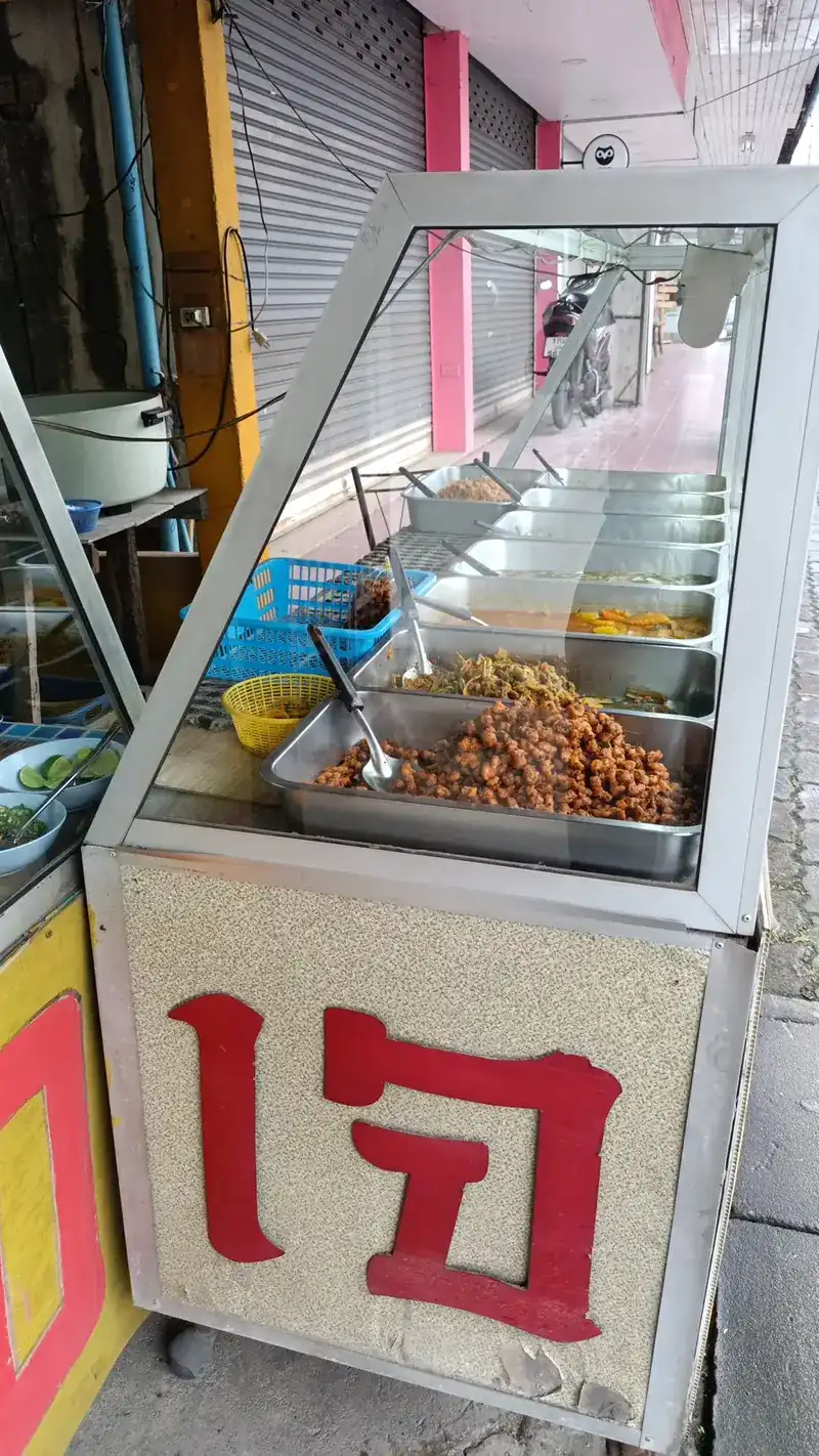 The steel food cart at the shop front, with a big red เจ on its side