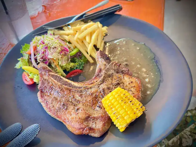 Pork chop with fries, salad, grilled corn and gravy