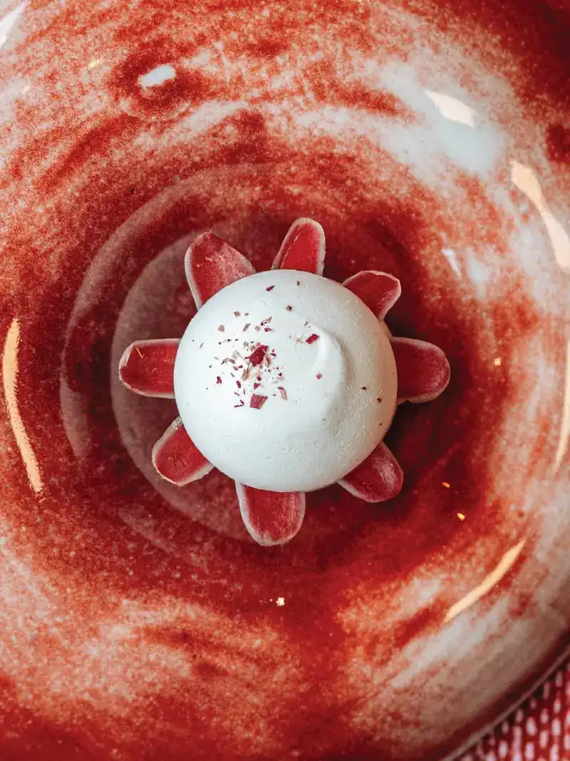 A white dome ringed with red petals on a red swirled plate