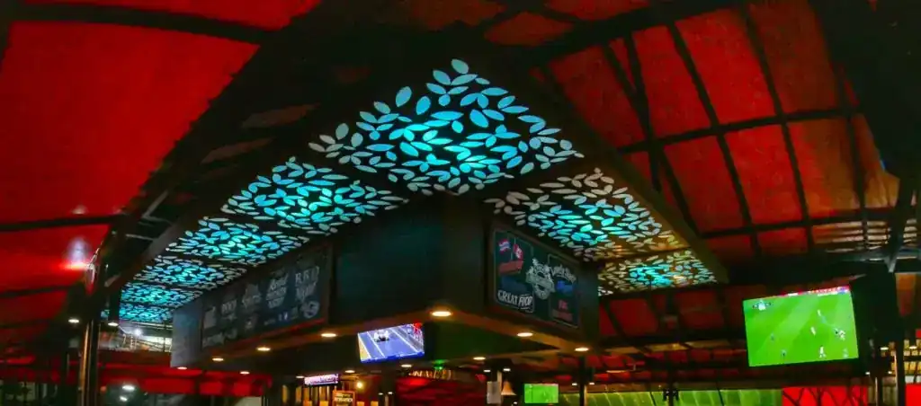 The glowing leaf-pattern canopy over the bar under the red roof, with football on the screens