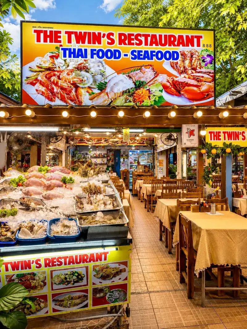 The front of The Twin’s Restaurant: the yellow sign, seafood on ice by the entrance and the tables behind