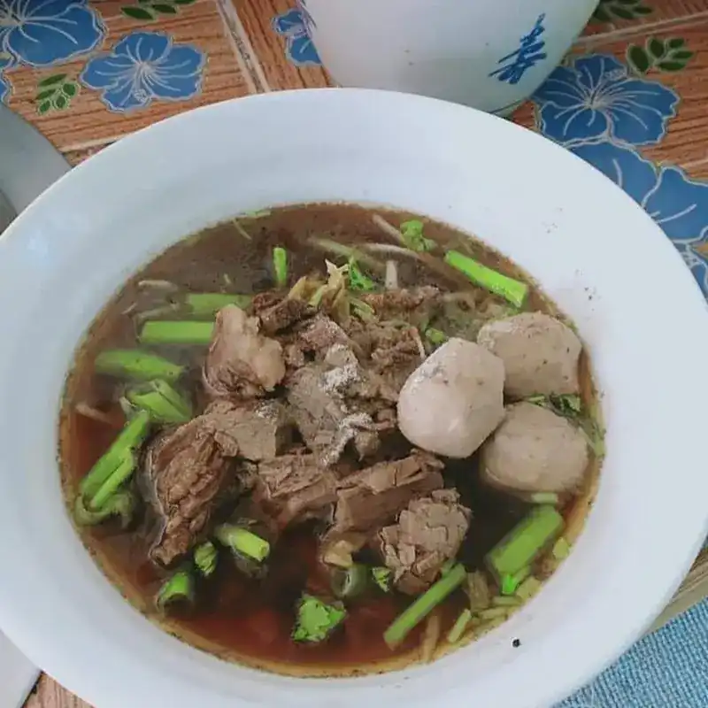 Beef and meatballs in a dark broth with greens