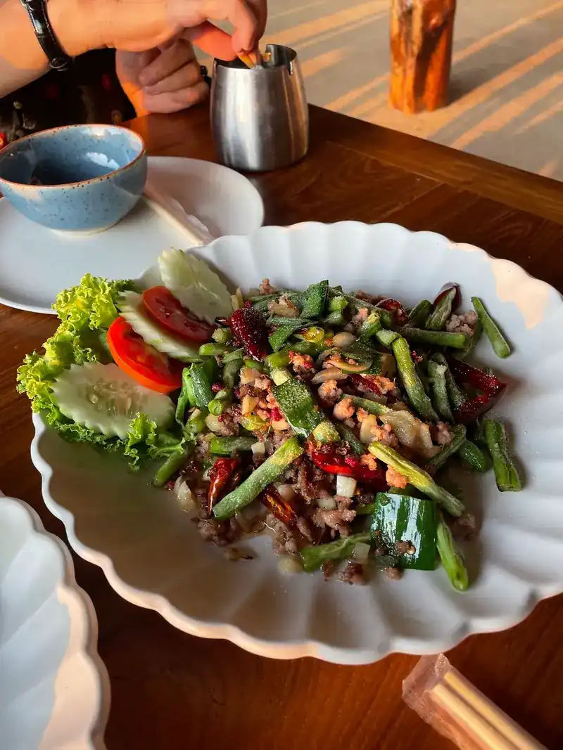 A stir-fry with long beans and chilli, with lettuce, tomato and cucumber on the side