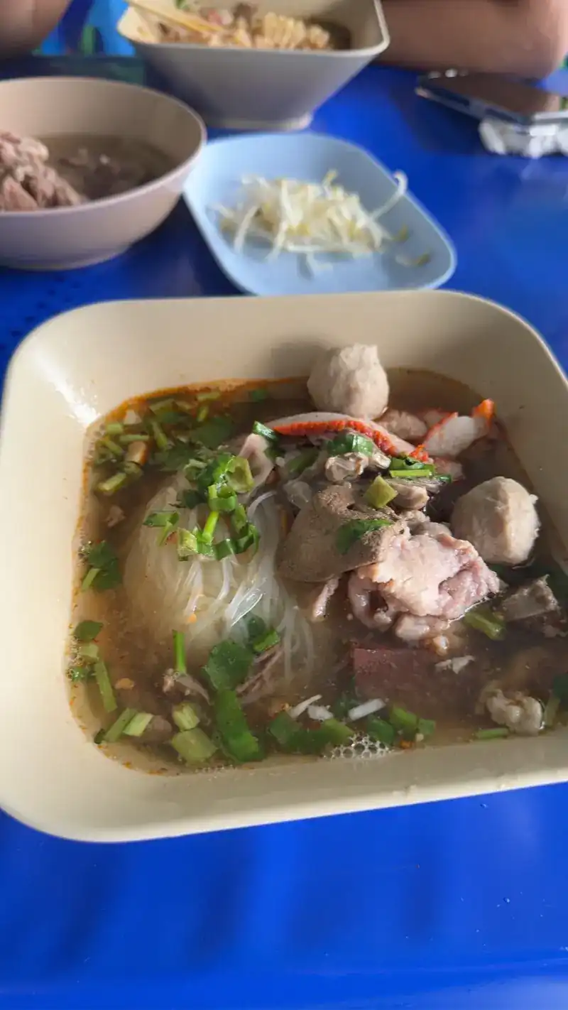Noodle soup with rice vermicelli, meatballs, pork and spring onions on a blue table