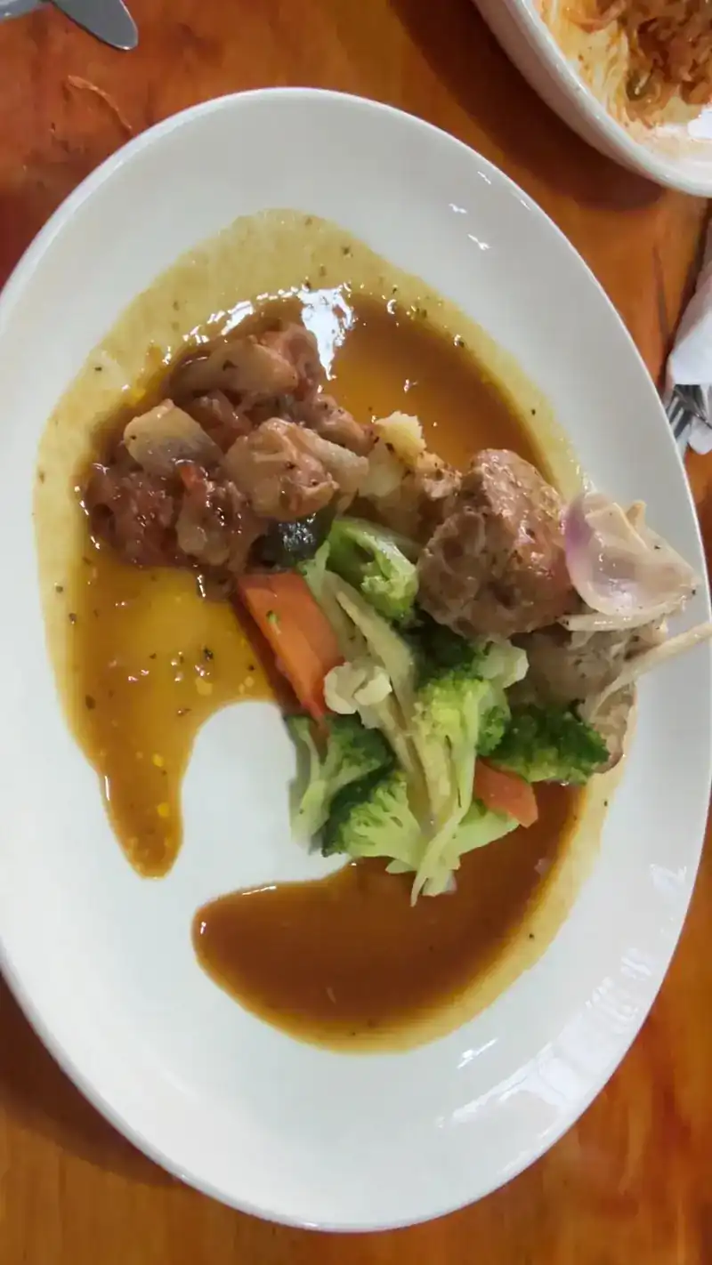 Stir-fried meat with broccoli and carrot in a brown sauce on a white plate