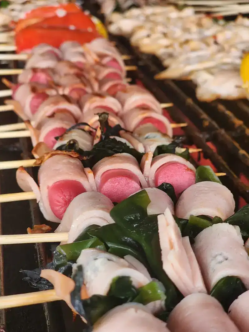 Rolled and wrapped skewers lined up on the grill