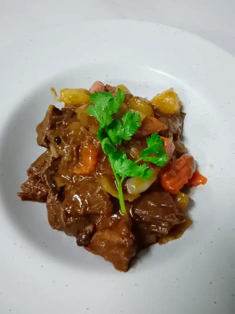 Beef stew in a white bowl, with coriander on top