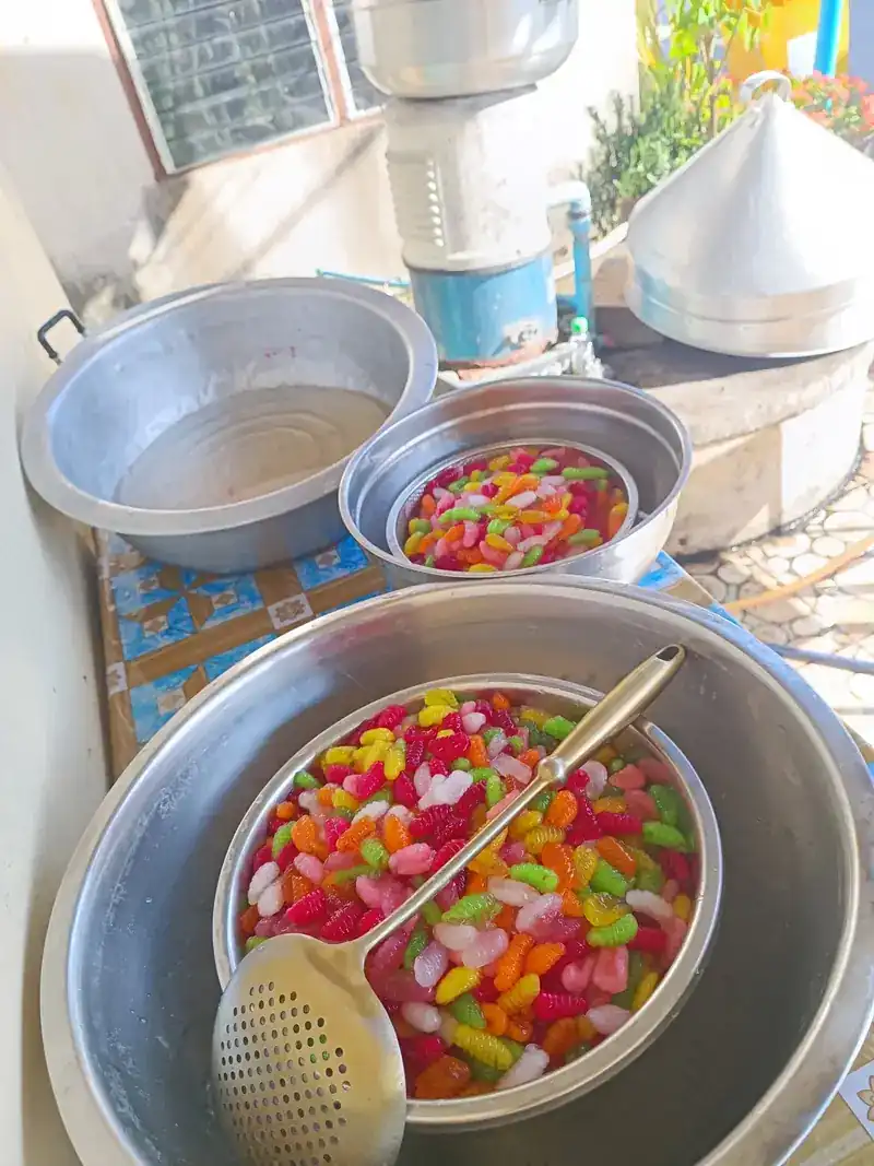 Bright pink, green and orange pieces draining in a colander over a basin