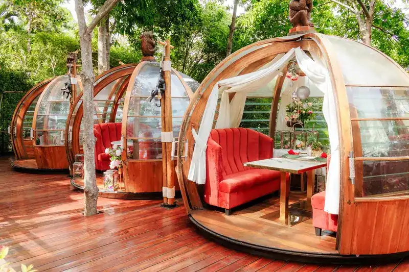 A timber dome with white curtains tied back, a red sofa and a table laid for two