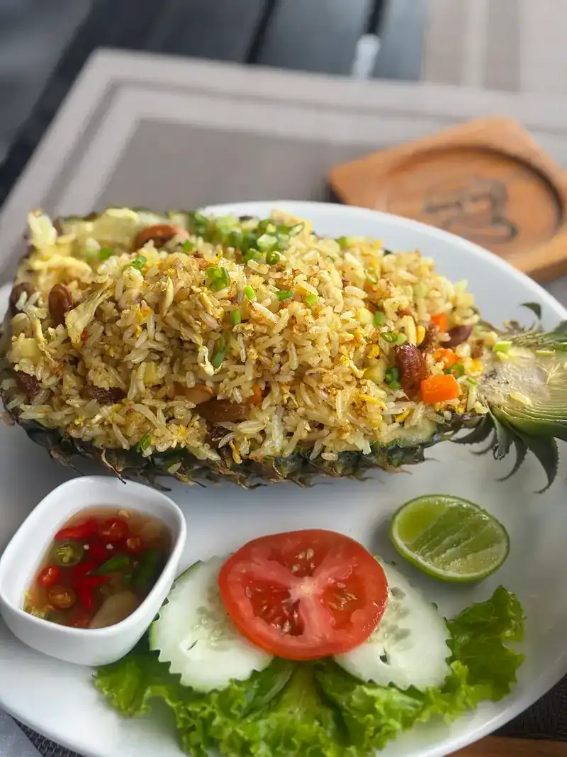 Pineapple fried rice served in half a pineapple, with cucumber, tomato and chilli sauce / ข้าวผัดสับปะรดเสิร์ฟในลูกสับปะรด พร้อมแตงกวา มะเขือเทศ และน้ำปลาพริก
