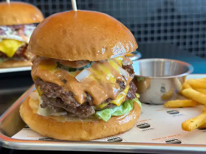 Double beef patties with melted cheese and sauce in a glossy bun / เนื้อสองชั้น ชีสละลาย และซอส ในขนมปังเงา