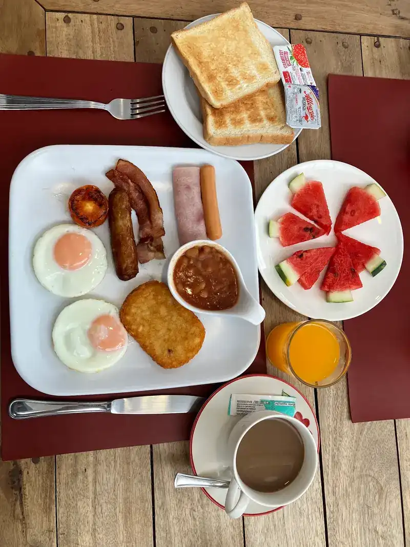 Breakfast from above: fried eggs, bacon, sausages, hash brown, beans, toast, watermelon, orange juice and coffee
