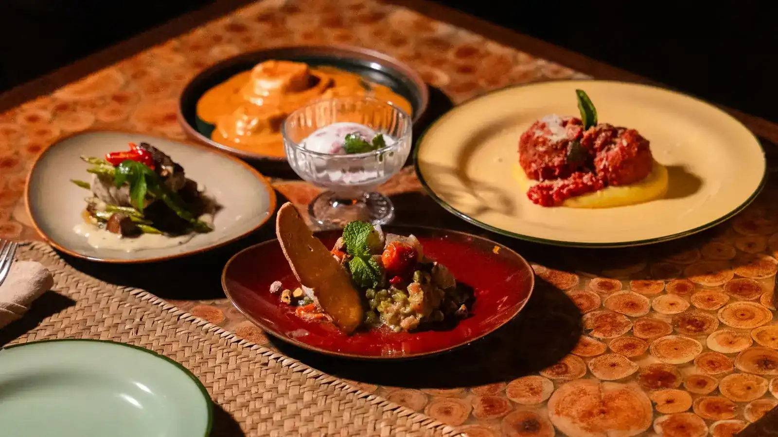 Plates of Italian dishes on a wooden table in warm evening light