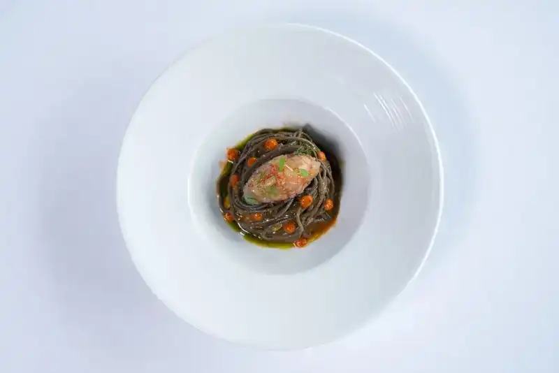 A dark pasta plate with a seafood topping, seen from above