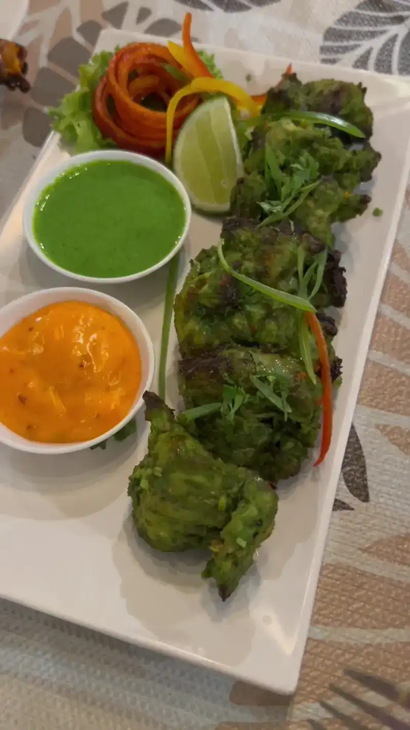 Green-marinated tikka on a long plate with green and orange dips