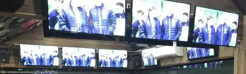 A wall of TV screens above the bar, all showing the same match