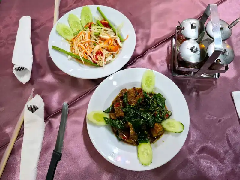 Papaya salad, and crispy pork stir-fried with basil, on a purple tablecloth