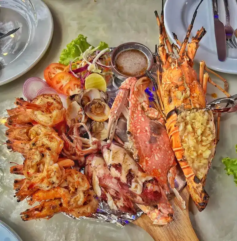 A grilled seafood platter: prawns, squid, crab, clams and a lobster topped with garlic
