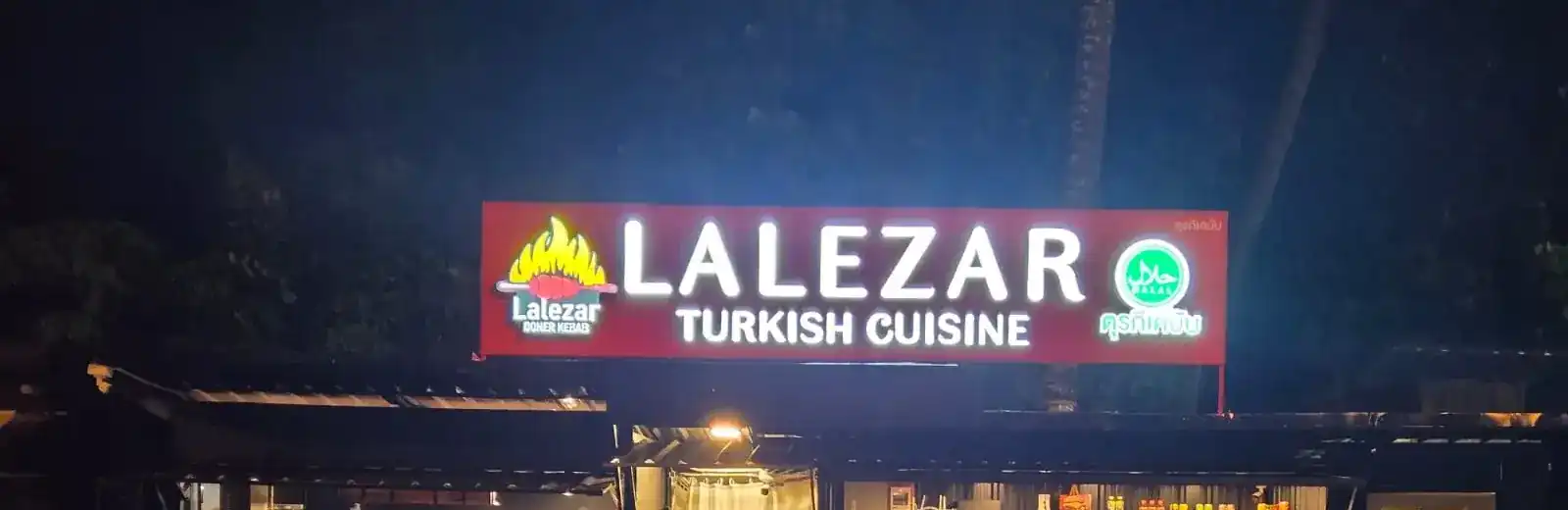 Lalezar's red sign lit up at night over the stall, Turkish Cuisine with the halal mark