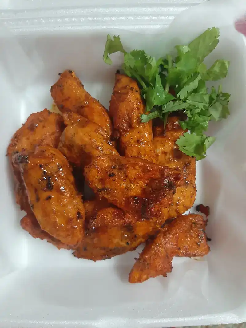 Spiced grilled chicken pieces with coriander in a take-away box