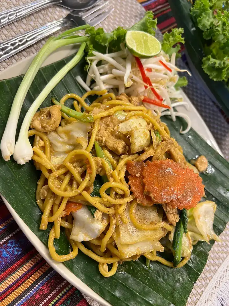 Stir-fried yellow noodles with vegetables on a banana leaf
